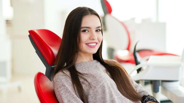 woman setting in a red dental chair