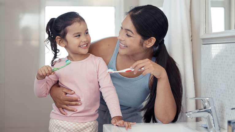 mother and her daughter holding toothbrush