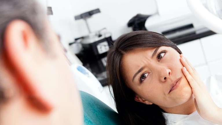 Woman holding her cheeks during dental emergency